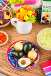 A handmade dollhouse miniature replica of a Mexican Talavera pottery plate with realistic avocados and onions.