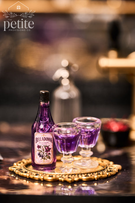 Handcrafted 1:12 scale Belladonna Nightshade Cordial Service with a translucent purple botanical-labeled bottle and two filled violet cordial glasses on an ornate gold tray.