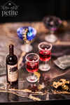 A bottle of Black Rose Cellars Merlot wine with two small glasses filled with red wine.