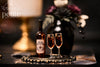 Handcrafted 1:12 scale Dead Reckoning Dark Rum Service featuring an amber rum bottle and two filled stemmed glasses on an ornate black and antique-gold tray.