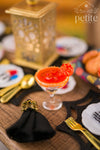 Handcrafted 1:12 scale Flor de Cempasúchil Margarita with an orange marigold garnish and colorful rim, displayed beside a black napkin with a gold ribcage ring and miniature gold flatware.