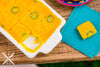 A close-up of a dollhouse miniature replica of a freshly baked jalapeño cornbread square. The cornbread is moist and fluffy, with a hint of spice from the jalapeños.