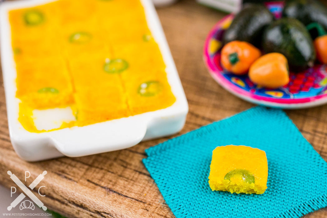 A one inch scale version of a beautiful and inviting dish of jalapeño cornbread. The cornbread is perfectly cooked, and the jalapeños add a touch of heat and spice. This dish is sure to please everyone at the table.