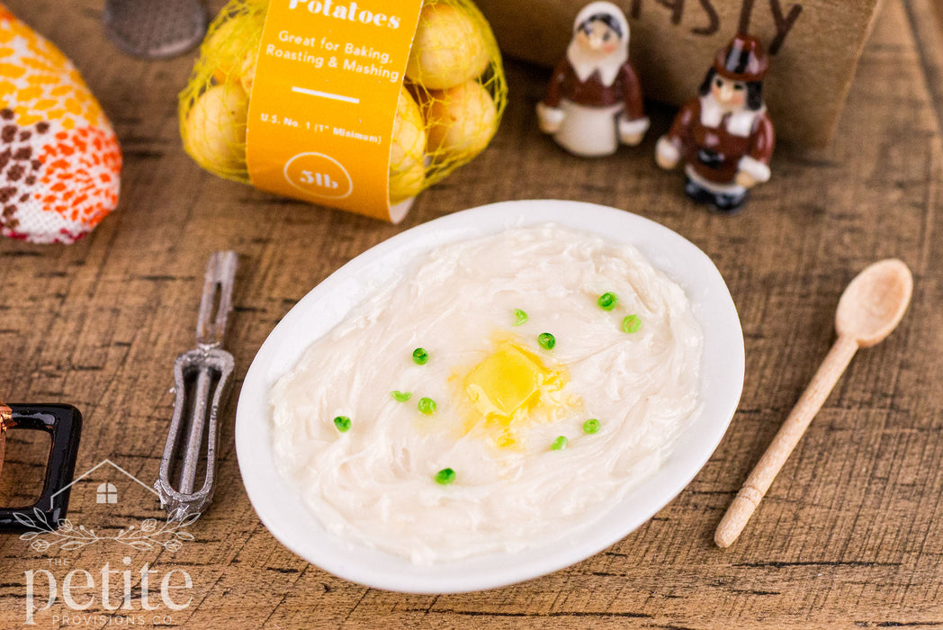 Oval white dish filled with sour cream and onion mashed potatoes, topped with a pat of melting butter and scattered green onions.