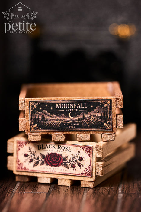 Stacked handcrafted miniature wine crates featuring Moonfall Estate moonlit vineyard and Black Rose Cellars botanical labels in a 1:12 scale Art Deco bar setting.